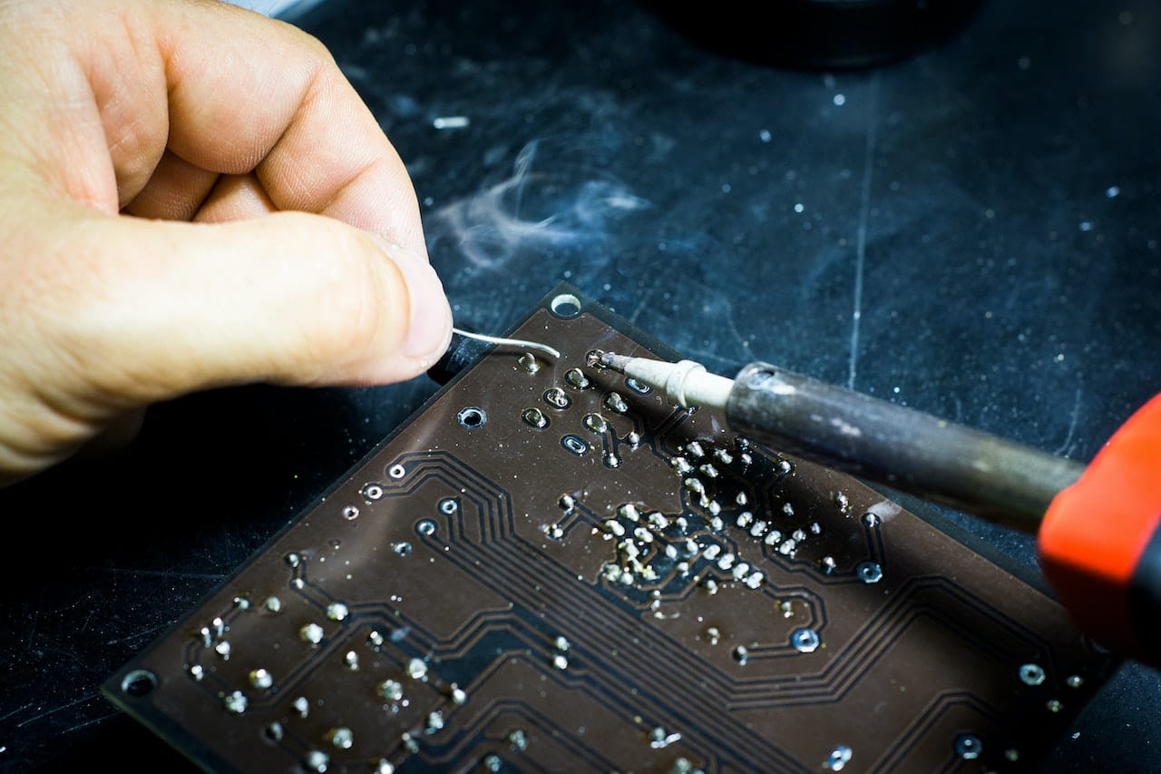 A person Soldering new components onto a circuit board after diagnosing a fault